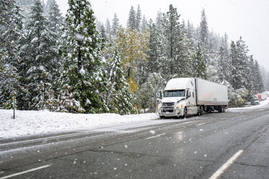 Semi-truck driving through snow and winter conditions.