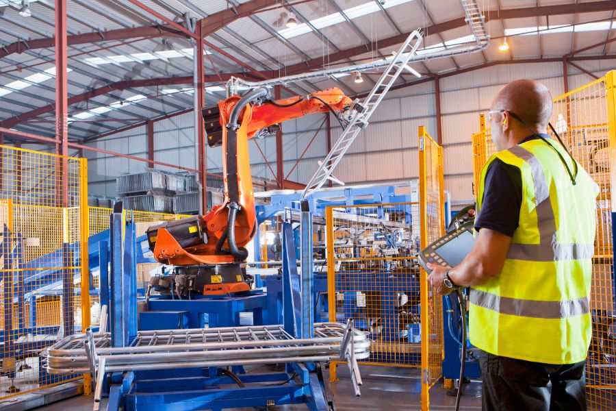Worker controlling robotic machinery lifting steel fencing,  representing supply chain trends in manufacturing