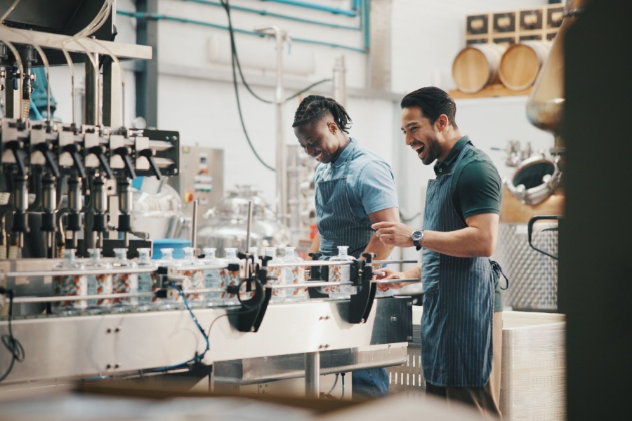 Two male workers bottle beverages on a conveyor line.