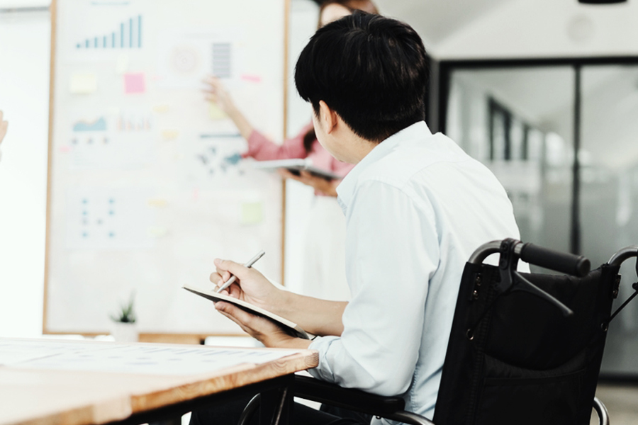 Ryder employee using a wheelchair working at a whiteboard in an office Ryder employee using a wheelchair working at a whiteboard in an office