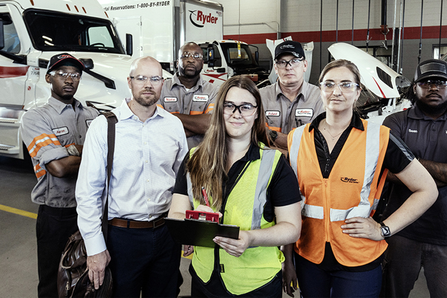A group of Ryder technicians and staff gathered together in a maintenance shop A group of Ryder technicians and staff gathered together in a maintenance shop