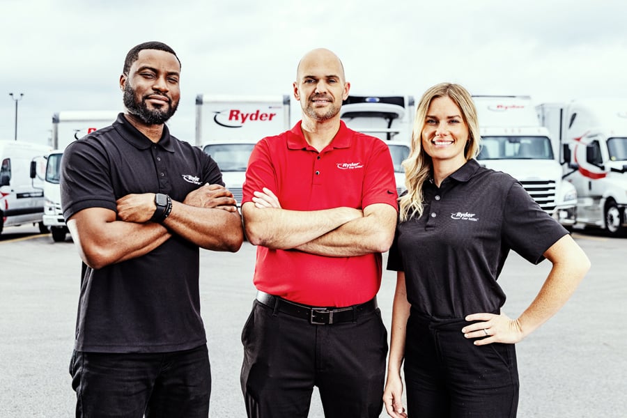 Three Ryder employees standing in front of a Ryder truck fleet Three Ryder employees standing in front of a Ryder truck fleet