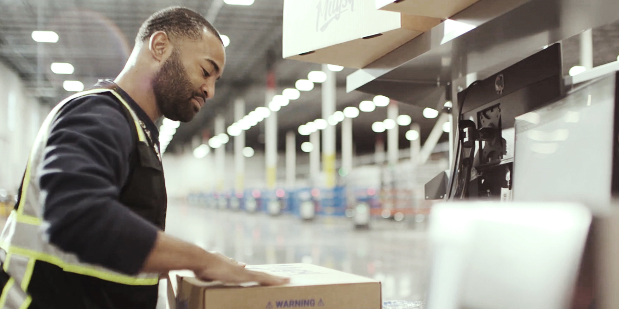 Ryder e-commerce fulfillment employee utilizing RyderShip and labeling boxes in a warehouse