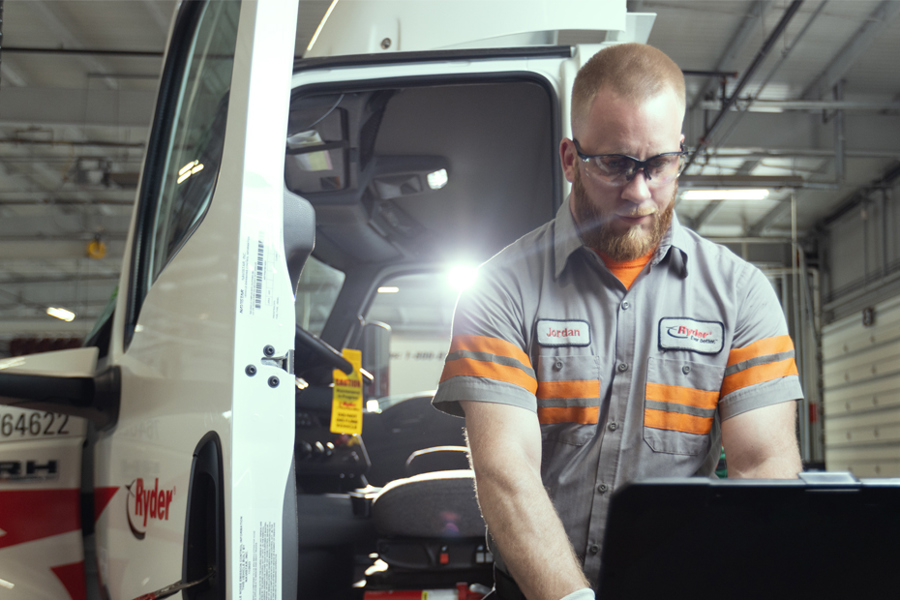 A Ryder technician performing maintenance on a semi-truck