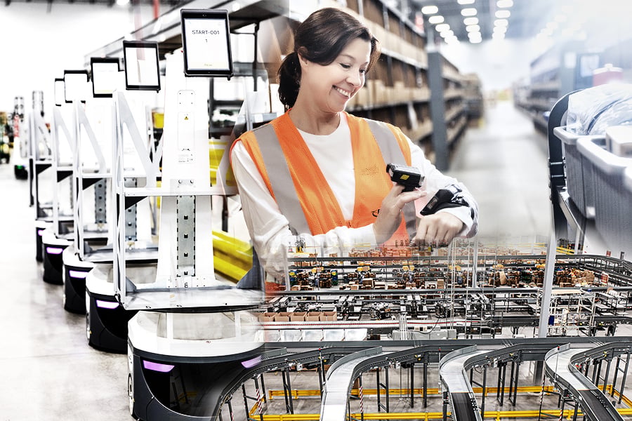 Ryder warehouse associate scanning a package beside automated warehouse robots