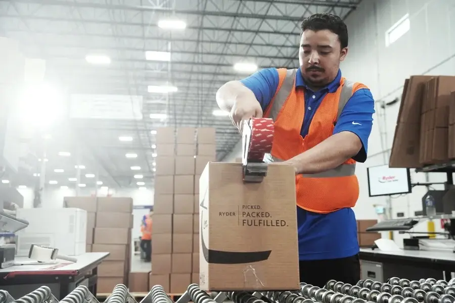 Ryder warehouse worker packing a fulfillment order into a branded bag Ryder warehouse worker packing a fulfillment order into a branded bag