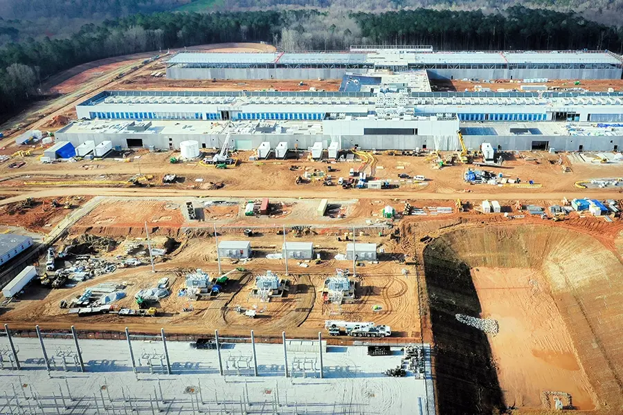 Data center construction site with buildings under development and construction equipment on cleared land Data center construction site with buildings under development and construction equipment on cleared landAerial view of a completed data center facility with rooftop cooling units