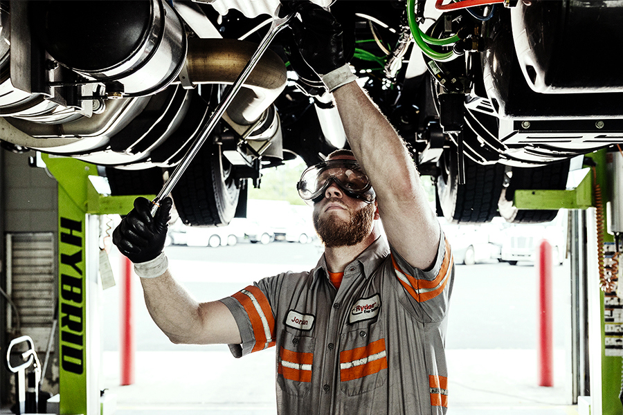 A mechanic performing maintenance on a semi-truck at a Ryder shop