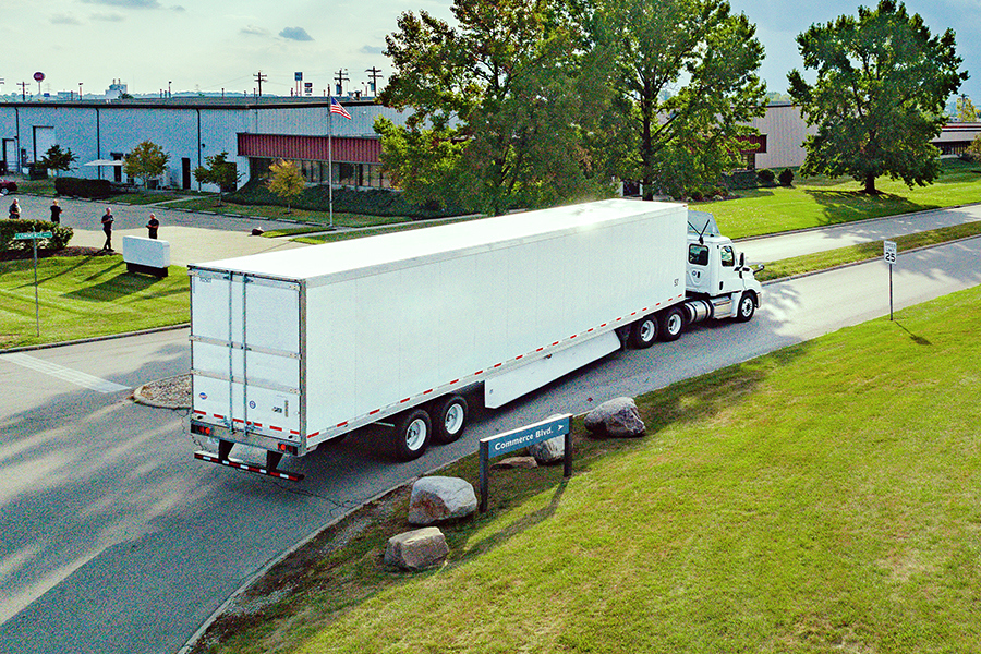 White Ryder semi truck with a dry van trailer turning onto a commercial park road White Ryder semi truck with a dry van trailer turning onto a commercial park road