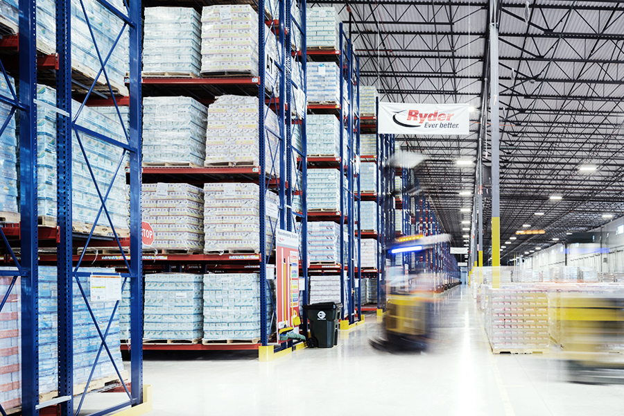 Forklift moving pallets through a large warehouse with high storage racks