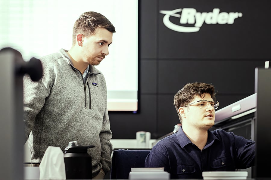 two Ryder transportation management employees working on a monitor